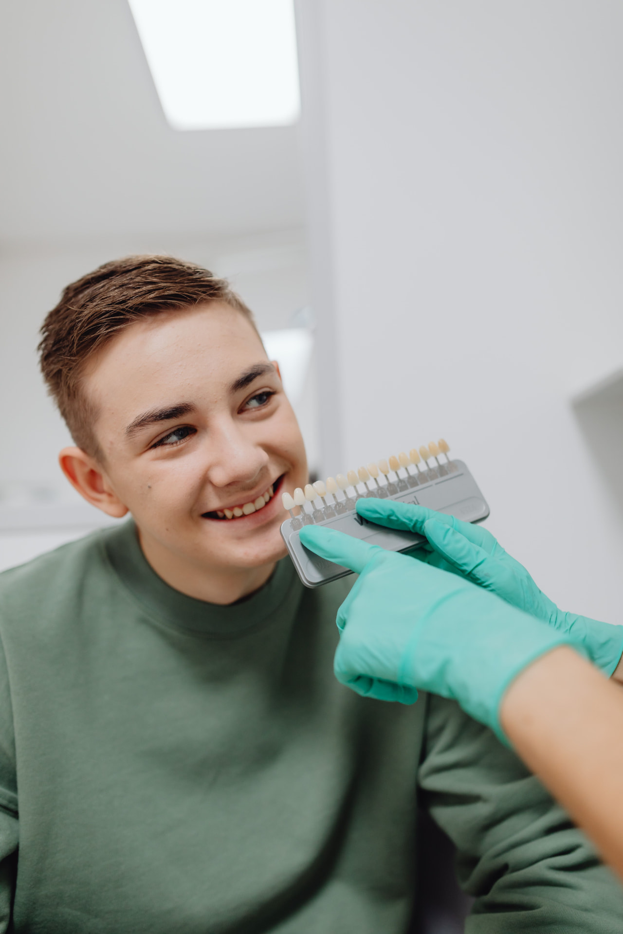 Paziente che sorride mentre si verifica il colore dei denti con una scala colori